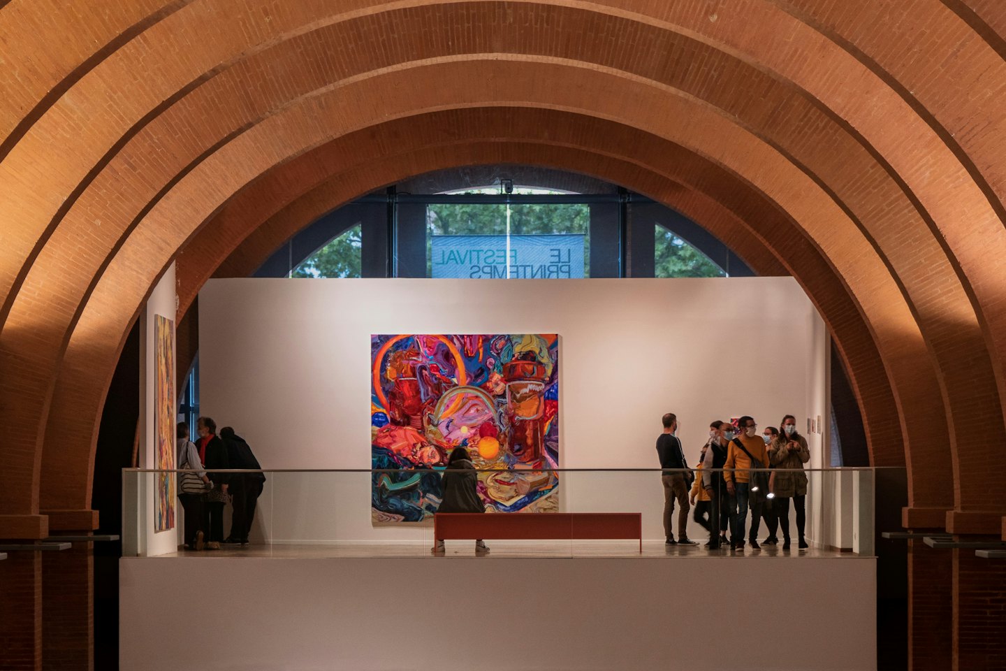 Visitatori osservano un grande quadro astratto in una galleria d'arte.